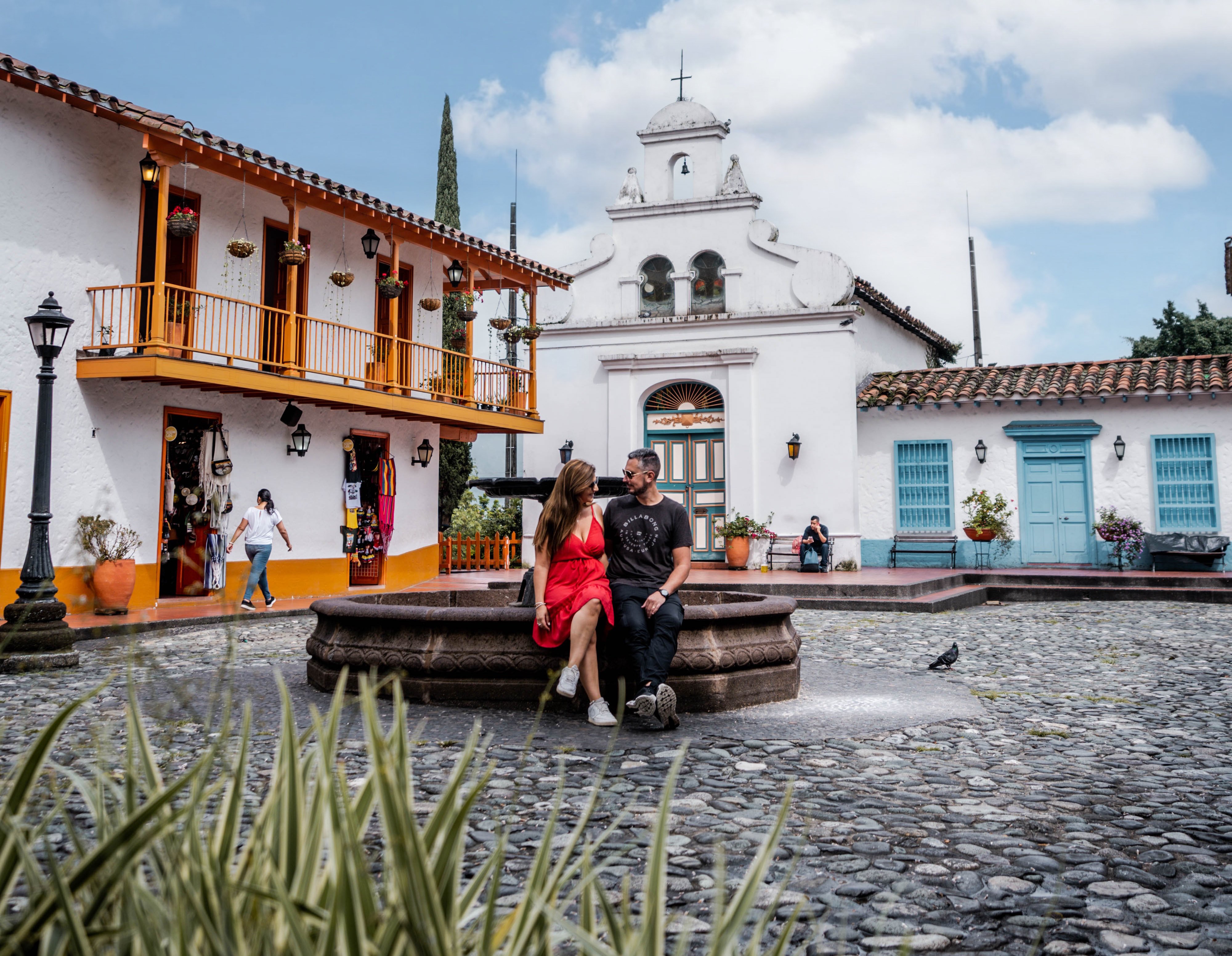 Pareja sentada en la fuente central de la plaza del pueblo paisa en Medellin.