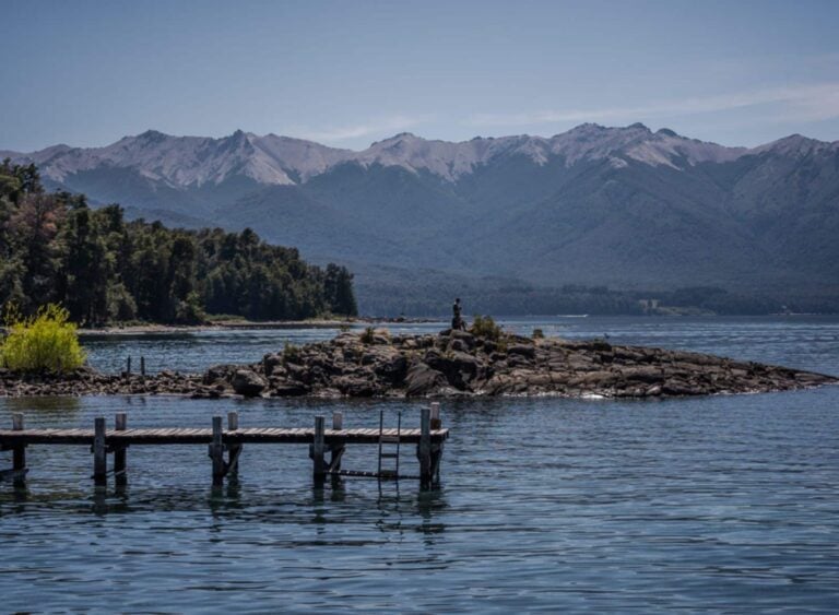 Muelle de madera sobre el lago con los Andes nevados en Bariloche