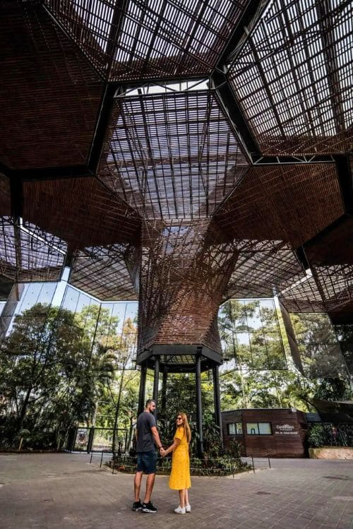 Pareja tomada de la mano bajo una estructura de madera en Medellín, Colmbia