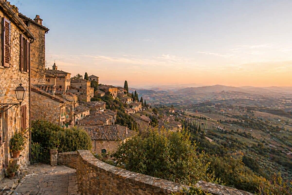 Calle en pendiente de Cortona con vista al valle al atardecer, Toscana